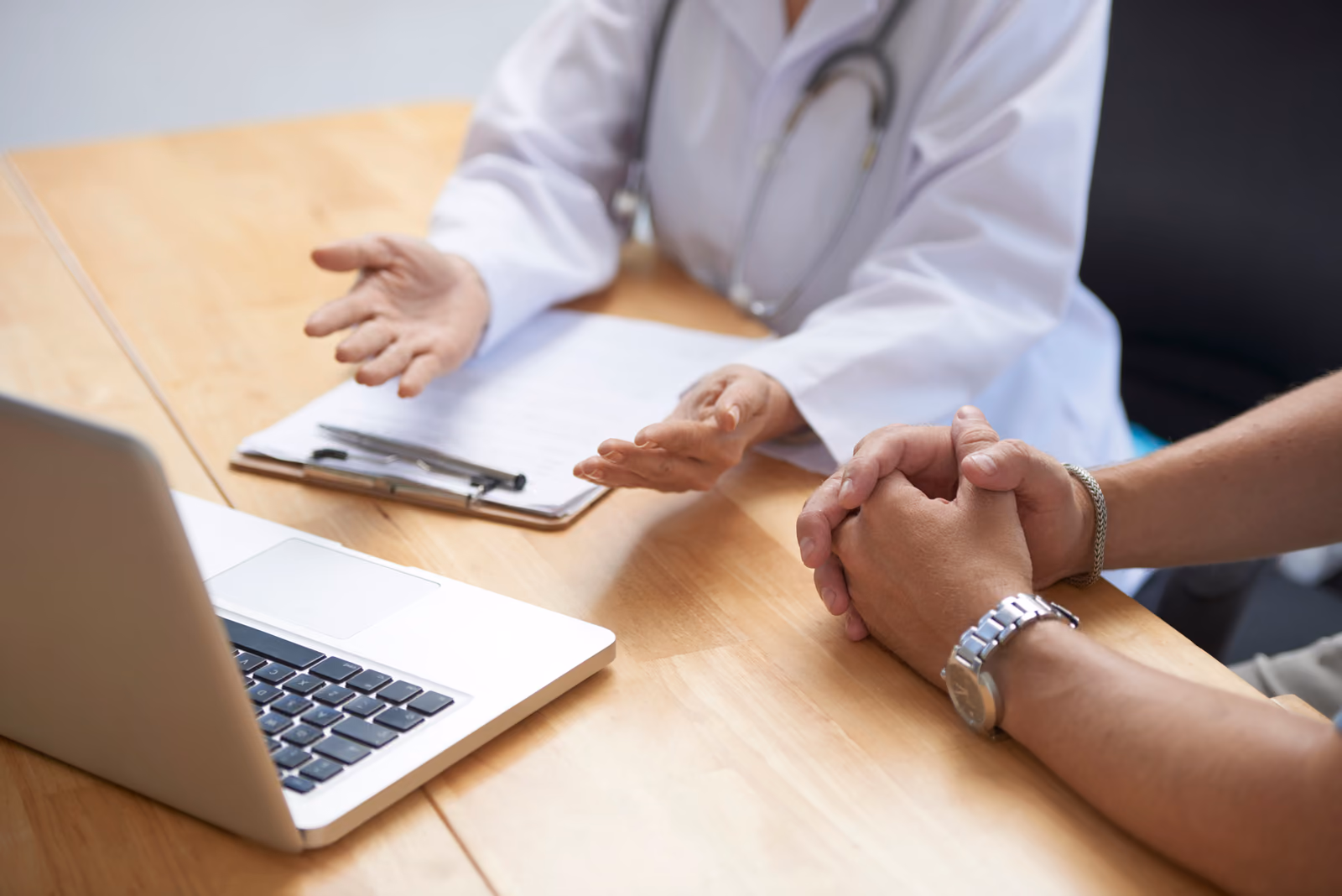 A doctor in a white coat talking through a plan with a patient across a desk